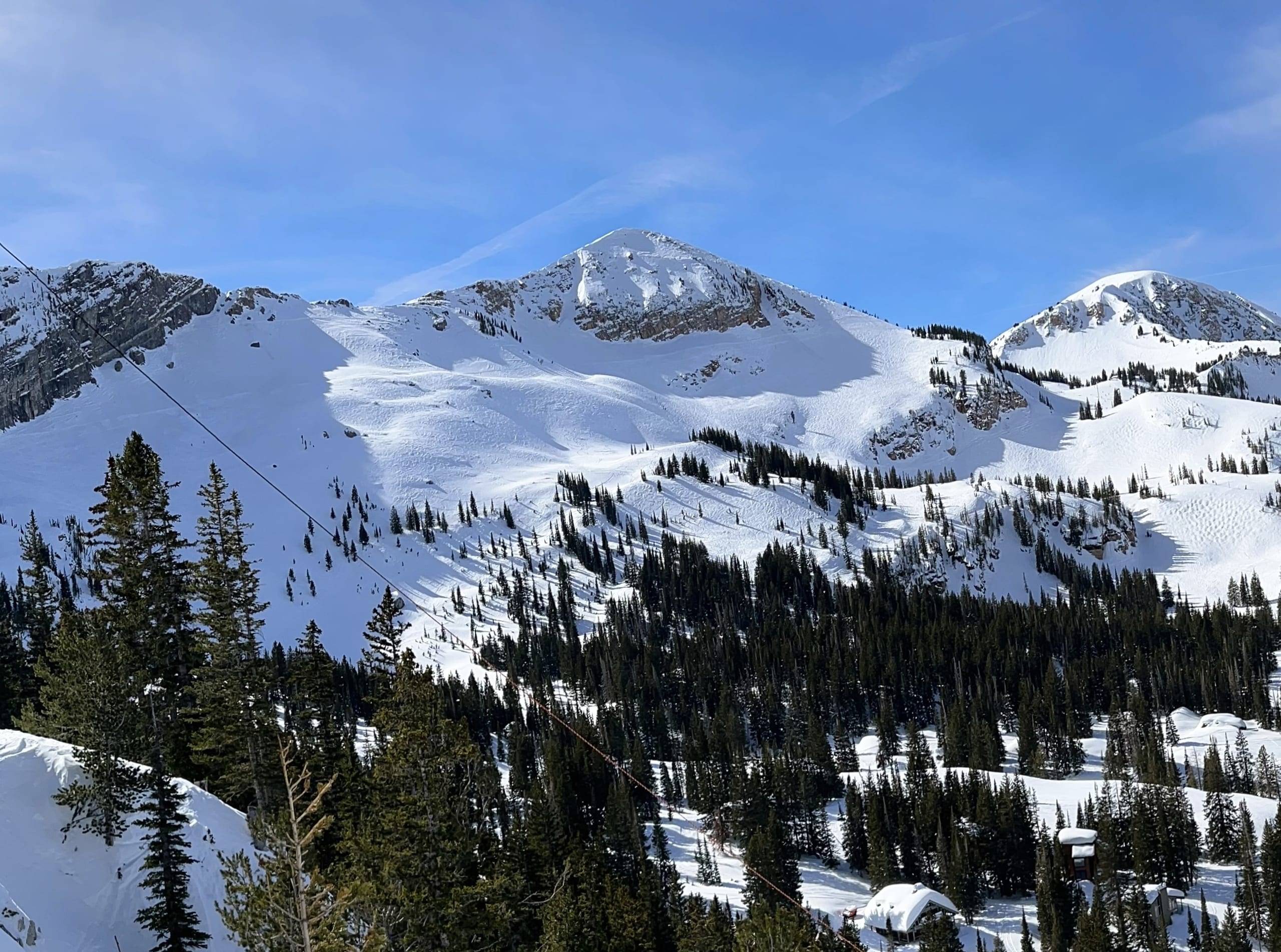 Snow-covered Sugarloaf Mountain and Mount Baldy above tracked, tree-dotted ski slopes at Alta, Utah.