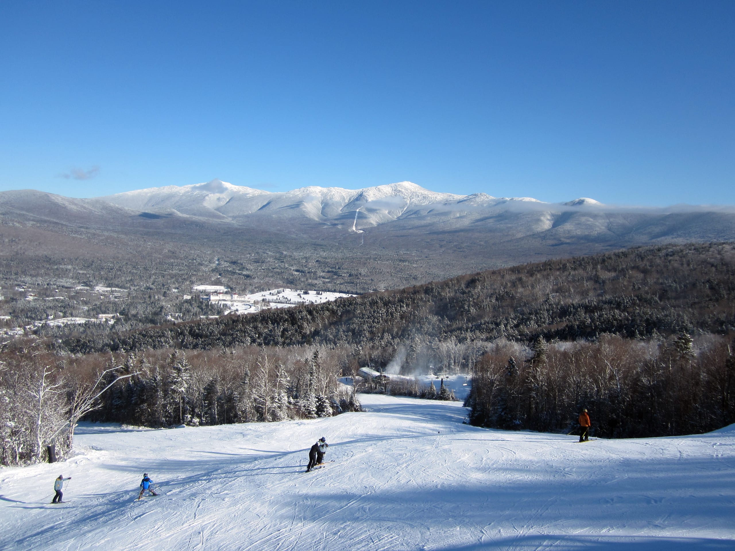 Skiers on a groomed trail at Bretton Woods with the snow-covered Presidential Range and Mount Washington beyond