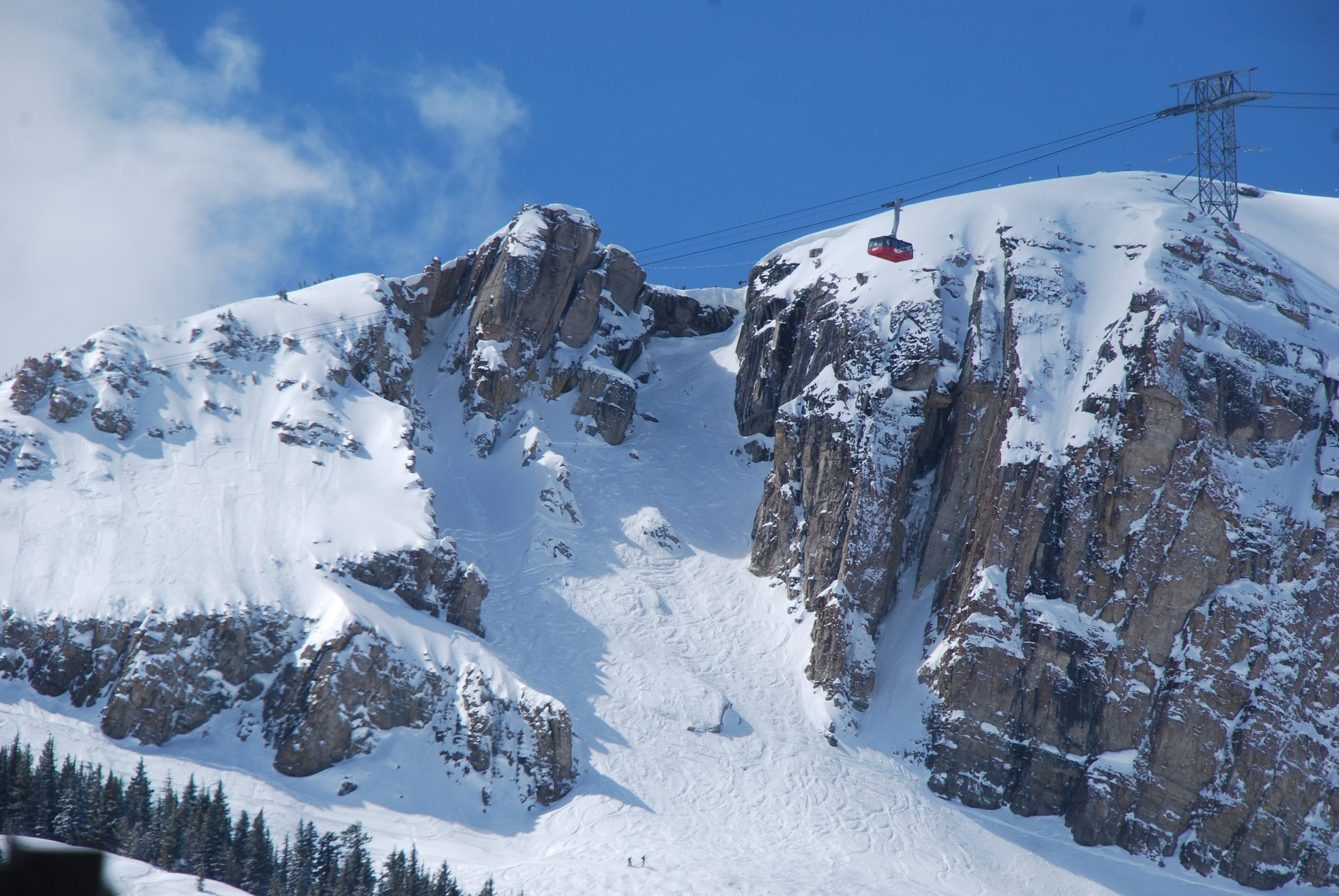 Corbet's Couloir on Rendezvous Mountain with the red aerial tram passing above snowy cliffs