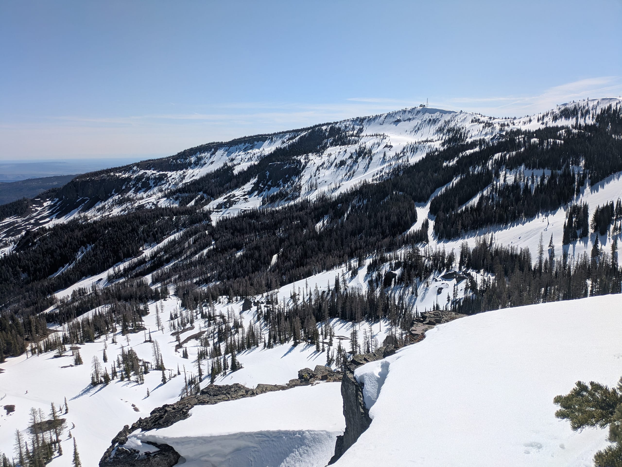 Snow-covered ridge with cut ski runs, glades and a summit tower at Mission Ridge in April