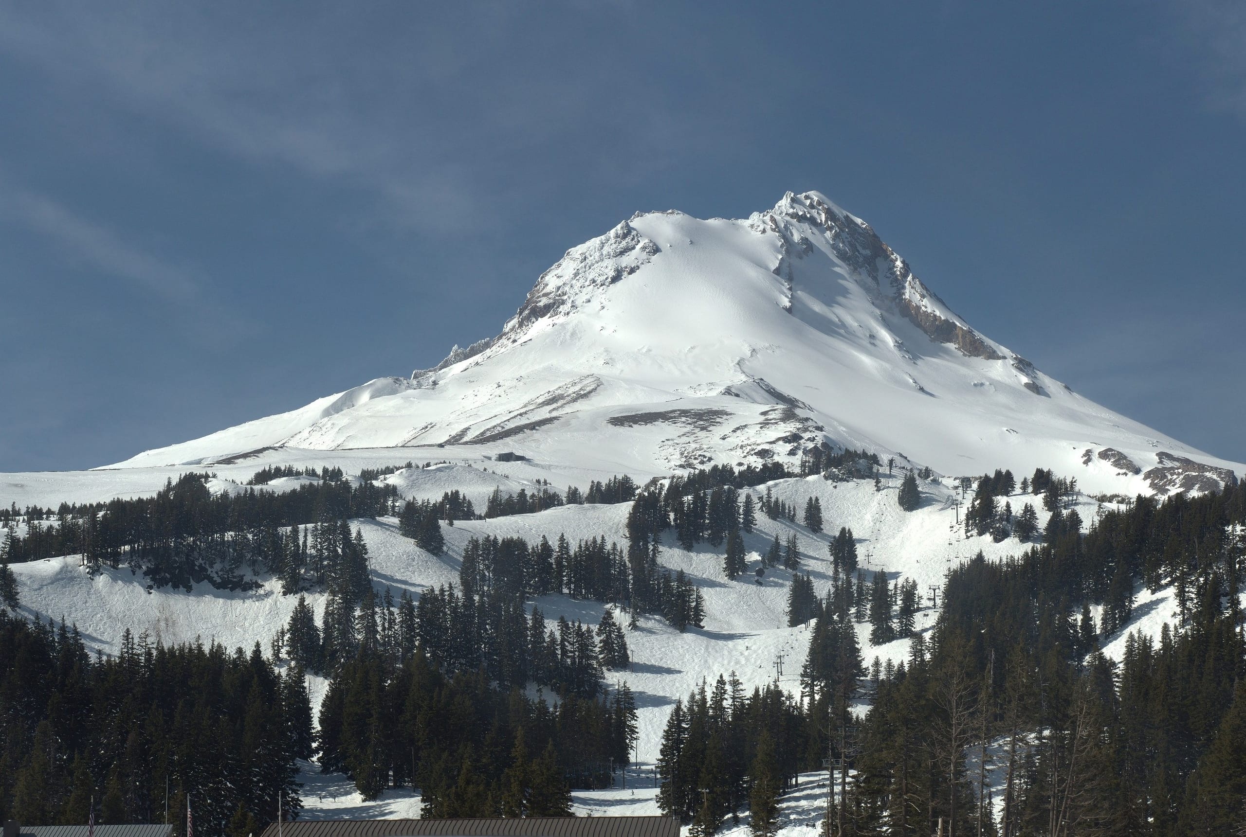 Snow-covered Mount Hood rising above the tree-lined ski slopes and lift line of Mount Hood Meadows