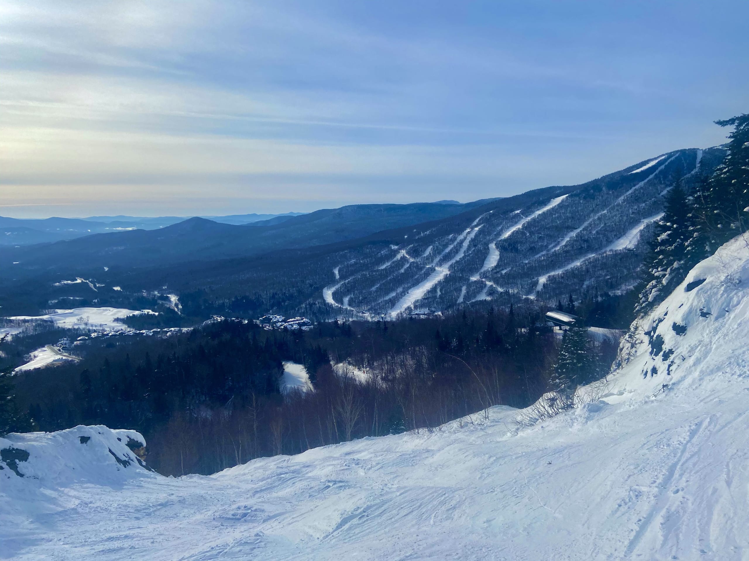 View from a snowy trail at Stowe, Vermont, looking across to a facing mountainside laced with ski trails