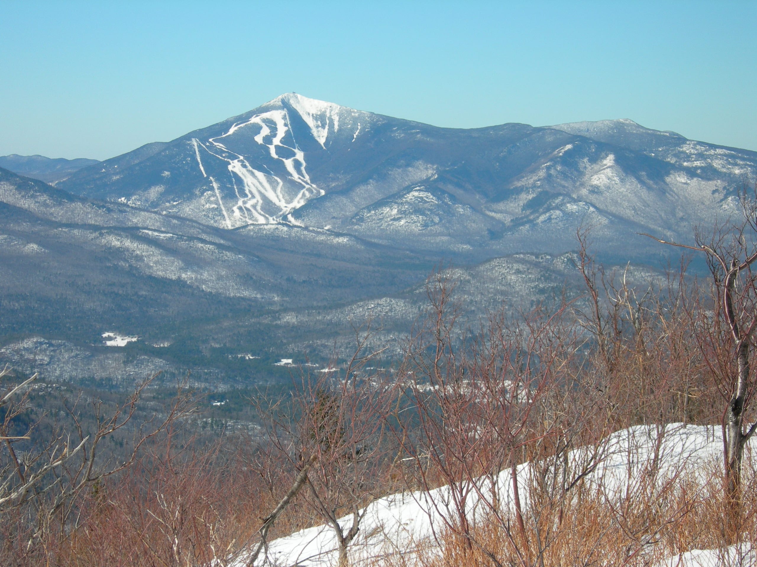Whiteface Mountain with its ski trails, seen across a forested valley from the Jay Mountain ridge in winter